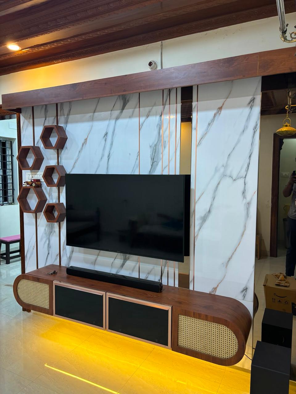 Living room TV unit with a marble-look wall panel and wood-and-cane console