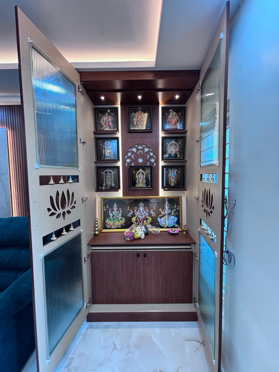 Pooja unit with a backlit shrine niche and decorative glass doors