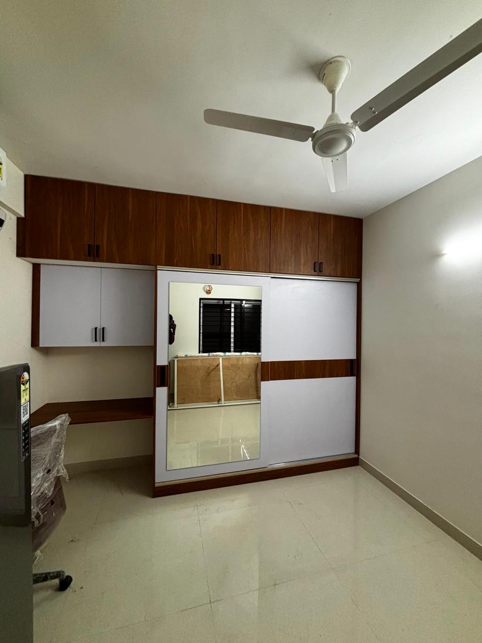 Bedroom with a built-in wardrobe, wood-finish panel and ceiling fan