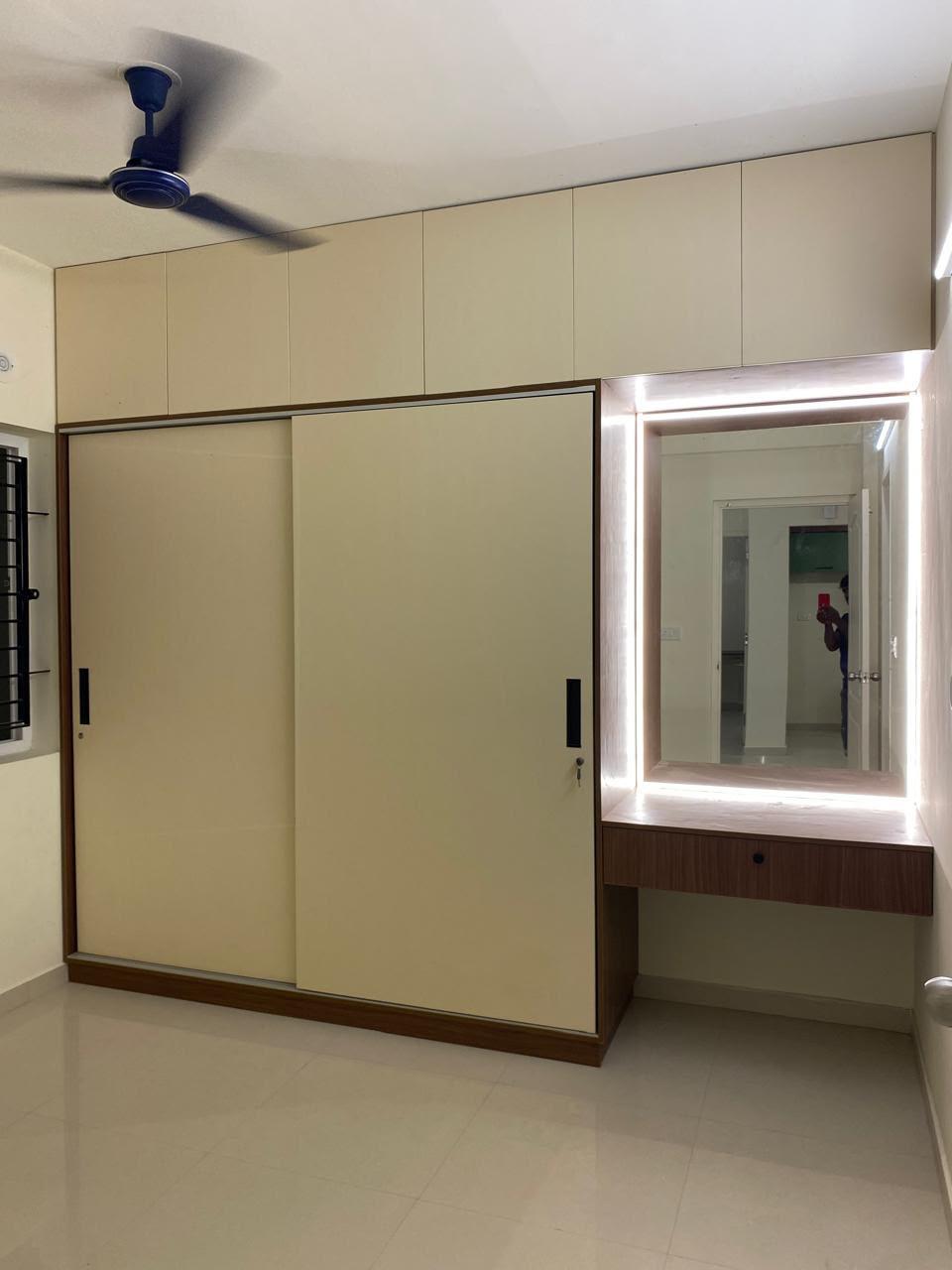 Bedroom with a beige sliding wardrobe and a lit dressing mirror