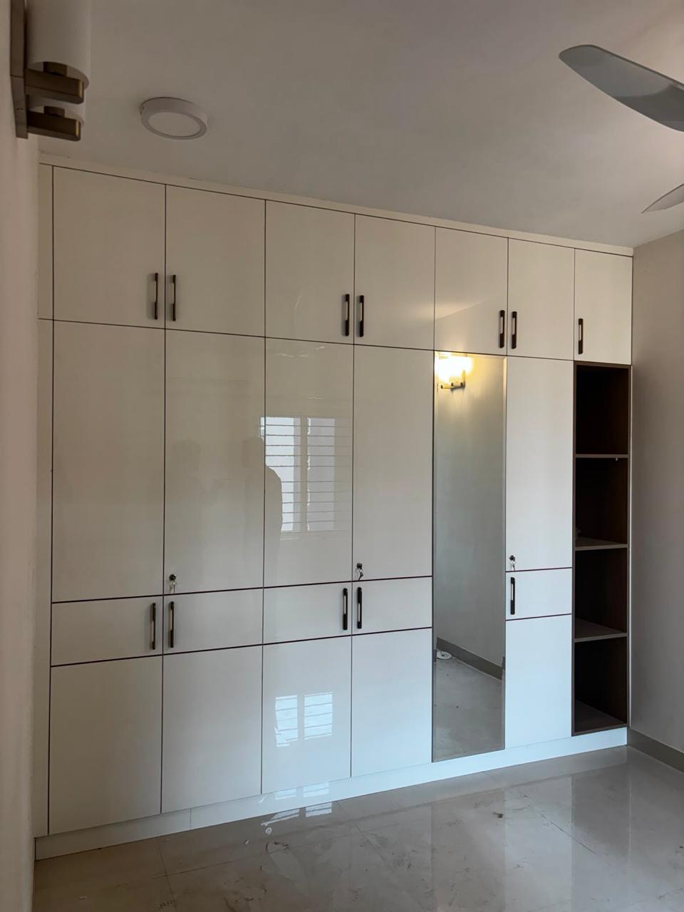 Floor-to-ceiling white wardrobe with a mirrored side panel