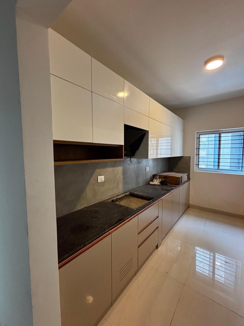 Modular kitchen with white overhead cabinets, grey base units and a black countertop